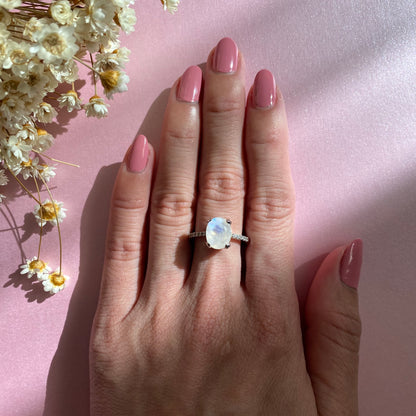 Model is wearing a large oval shape moonstone ring with cubic zirconia stones half pave band, 925 sterling silver, rhodium plated