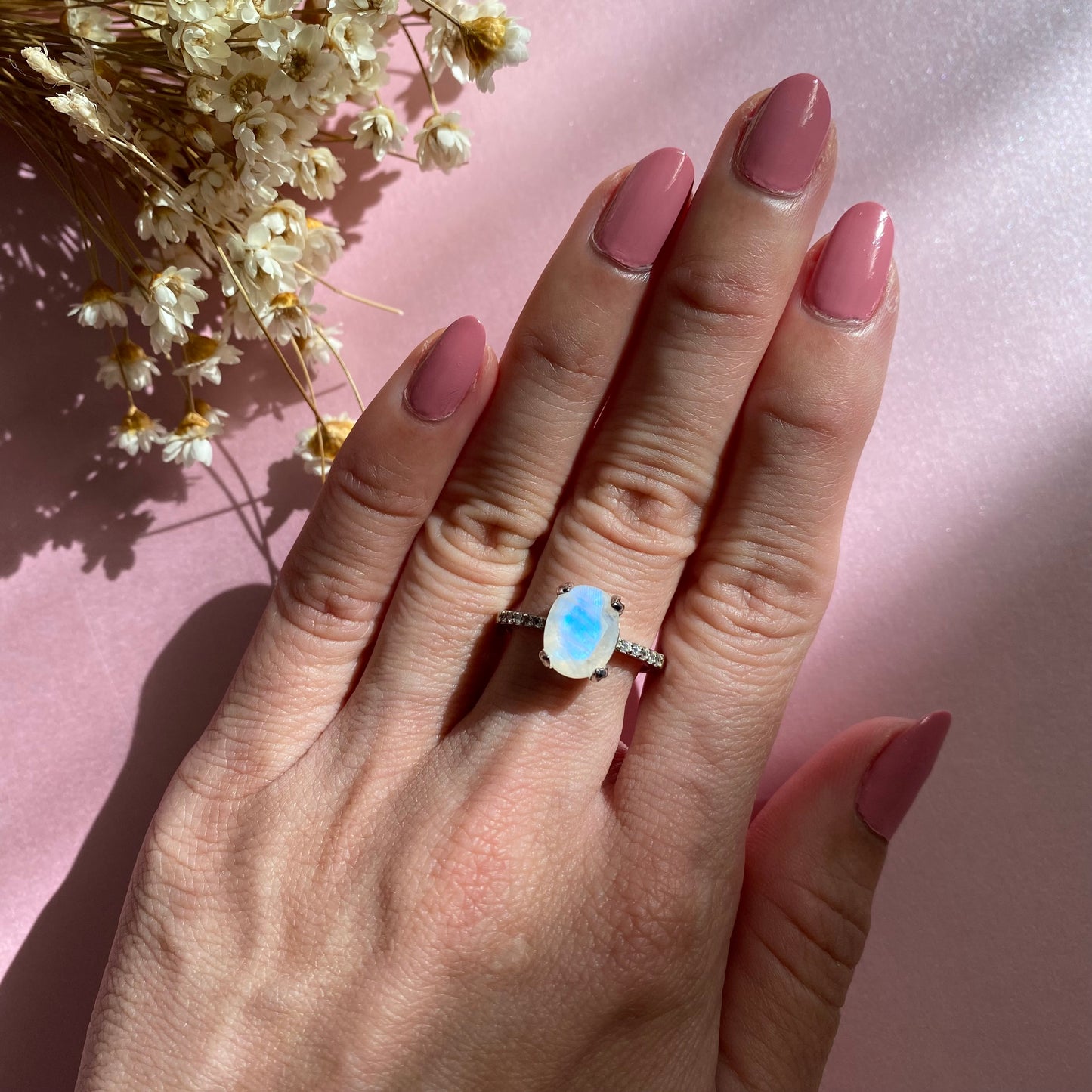 Model is wearing a large oval shape moonstone ring with cubic zirconia stones half pave band, 925 sterling silver, rhodium plated